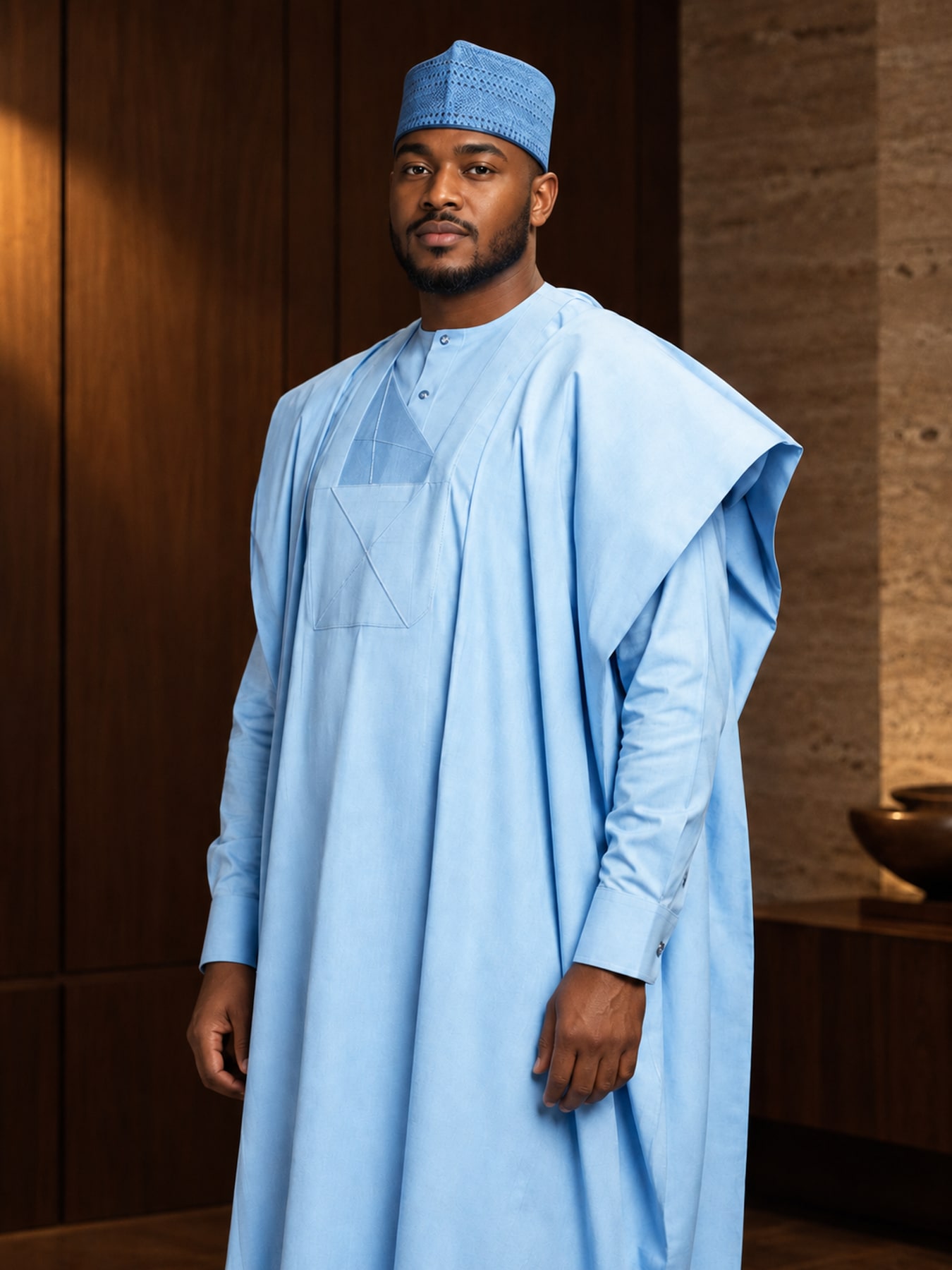 Nigerian man in a pale sky-blue babban riga with a tone-on-tone embroidered chest and matching cap